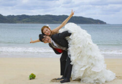 砂浜で新婦をおんぶする新郎